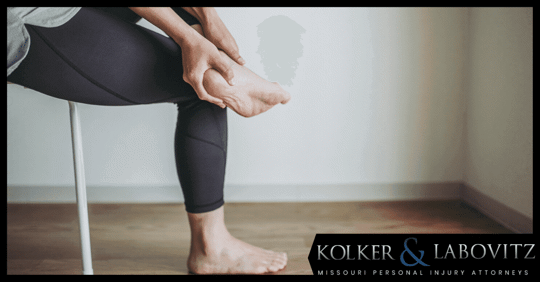 Person sitting in a chair, holding foot as if in pain.