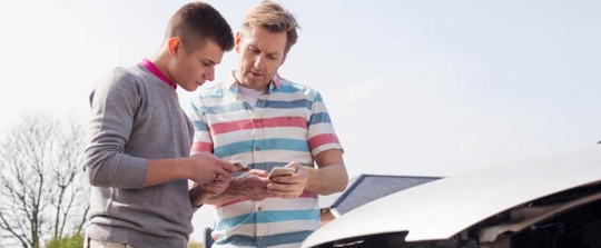 Two men exchanging insurance after car crash