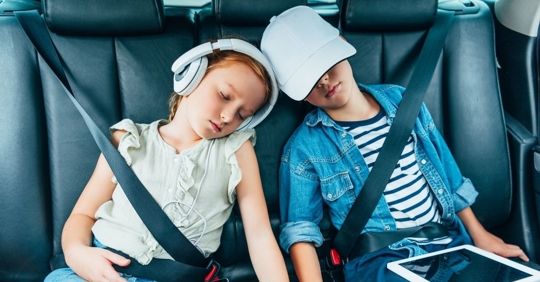 two kids sleeping in the backseat of a car