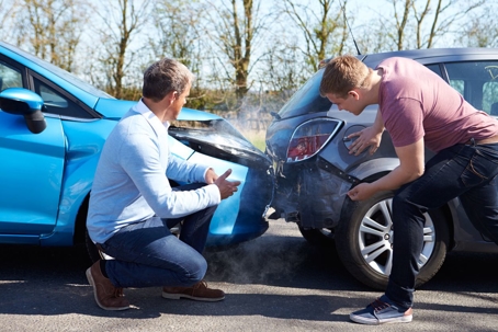 Two men looking at car crash damage